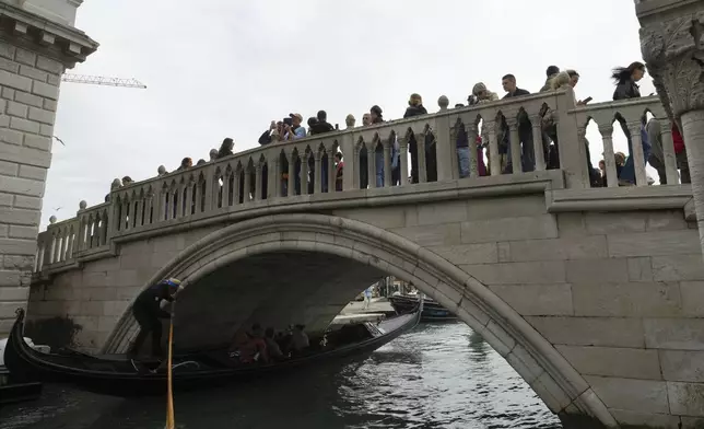 Tourists take pictures in San Marco square in Venice, Italy, Friday, April 18, 2025, Venice on Friday launches for a second year a pilot program to charge day-trippers an entrance fee. (AP Photo/Antonio Calanni)
