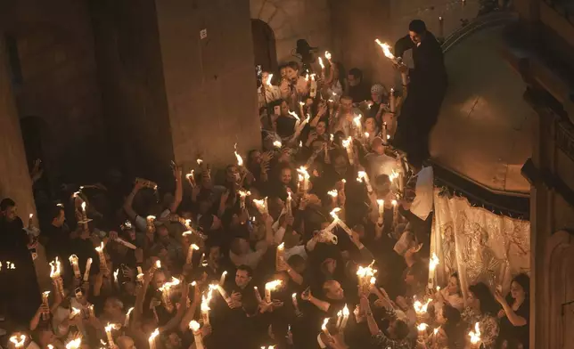 Christian pilgrims light candles during the Holy Fire ceremony, at the Church of the Holy Sepulcher, the site where according to tradition Jesus was crucified and buried, in Jerusalem's Old City, Saturday, April 19, 2025. (AP Photo/Mahmoud Illean)