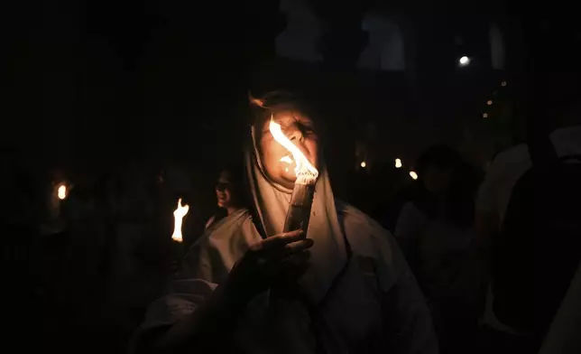 Christian pilgrims hold candles during the Holy Fire ceremony, at the Church of the Holy Sepulcher, the site where according to tradition Jesus was crucified and buried, in Jerusalem's Old City, Saturday, April 19, 2025. (AP Photo/Mahmoud Illean)