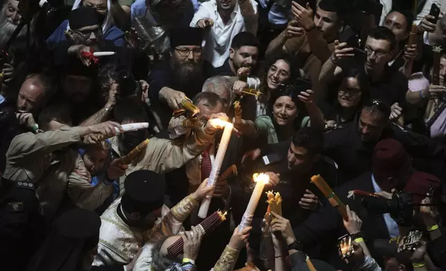 Christian pilgrims light candles during the Holy Fire ceremony, at the Church of the Holy Sepulcher, the site where according to tradition Jesus was crucified and buried, in Jerusalem's Old City, Saturday, April 19, 2025. (AP Photo/Mahmoud Illean)