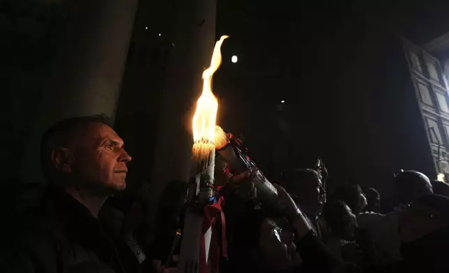 Christian pilgrims light candles during the Holy Fire ceremony, at the Church of the Holy Sepulcher, the site where according to tradition Jesus was crucified and buried, in Jerusalem's Old City, Saturday, April 19, 2025. (AP Photo/Mahmoud Illean)