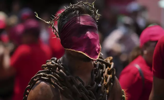 A masked penitent, wearing chains and a crown of thorns, takes part in a Holy Week procession in Atlixco, Mexico, on Good Friday, April 18, 2025. (AP Photo/Eduardo Verdugo)