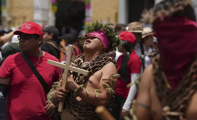 A masked penitent, wearing chains and a crown of thorns and cacti attached to his arms, takes part in a Holy Week procession in Atlixco, Mexico, on Good Friday, April 18, 2025. (AP Photo/Eduardo Verdugo)