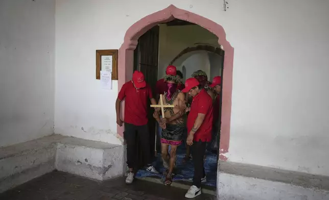 A masked penitent in chains is led to take part in a Holy Week procession in Atlixco, Mexico, on Good Friday, April 18, 2025. (AP Photo/Eduardo Verdugo)
