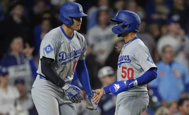 Los Angeles Dodgers designated hitter Shohei Ohtani (17), left, and Mookie Betts (50) celebrate after scoring on a double from Freddie Freeman during the seventh inning of a baseball game against the Chicago Cubs, Tuesday, April 22, 2025, in Chicago. (AP Photo/Erin Hooley)