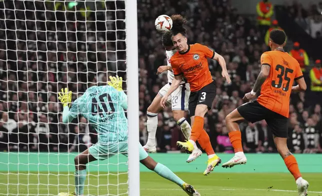Frankfurt's Arthur Theate, center, clears the ball before Tottenham's Brennan Johnson, background, can reach it during the Europa League quarterfinals first leg soccer match between Tottenham Hotspur and Eintracht Frankfurt at the Tottenham Hotspur Stadium in London, England, Thursday, April 10, 2025. (AP Photo/Frank Augstein)