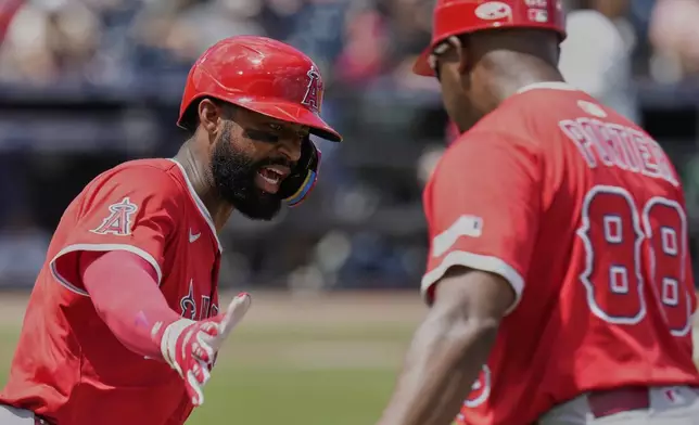 Los Angeles Angels' Jo Adell celebrates with first base coach Bo Porter (88) after hitting his second home run during the fifth inning of a baseball game against the Tampa Bay Rays Thursday, April 10, 2025, in Tampa, Fla. (AP Photo/Chris O'Meara)