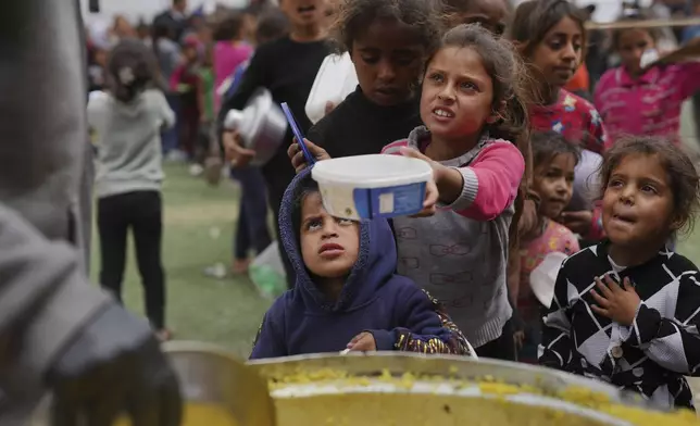 Palestinian children receive donated food at a distribution center in Nuseirat, central Gaza Strip, Friday, April 11, 2025. (AP Photo/Abdel Kareem Hana)