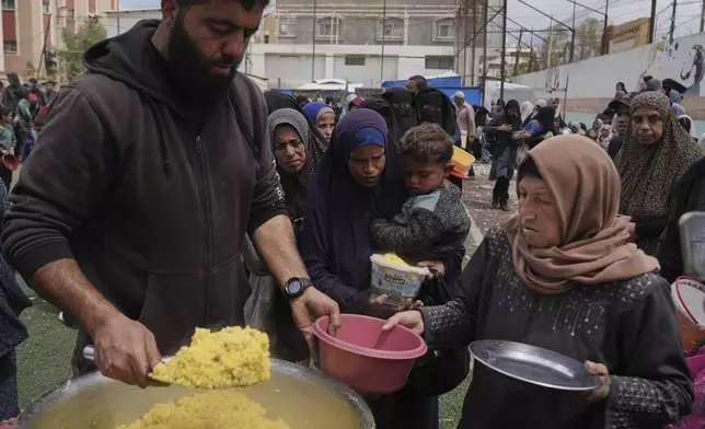 Palestinians receive donated food at a distribution center in Nuseirat, central Gaza Strip, Friday, April 11, 2025. (AP Photo/Abdel Kareem Hana)