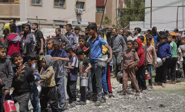 Palestinians wait for donated food at a distribution center in Nuseirat, central Gaza Strip, Friday, April 11, 2025. (AP Photo/Abdel Kareem Hana)