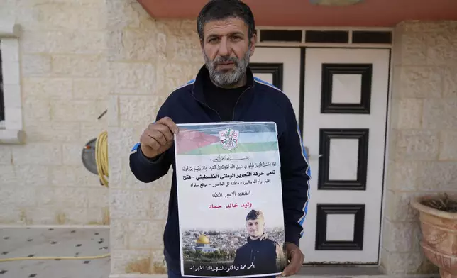 Khalid Ahmad holds a poster of his 17-year-old son, Waleed, who died in an Israeli prison, that reads in Arabic, "The hero prisoner Martyr, mercy and eternity for our righteous Martyrs," in the West Bank town of Silwad, northeast of Ramallah Wednesday, March 26, 2025. (AP Photo/Nasser Nasser)