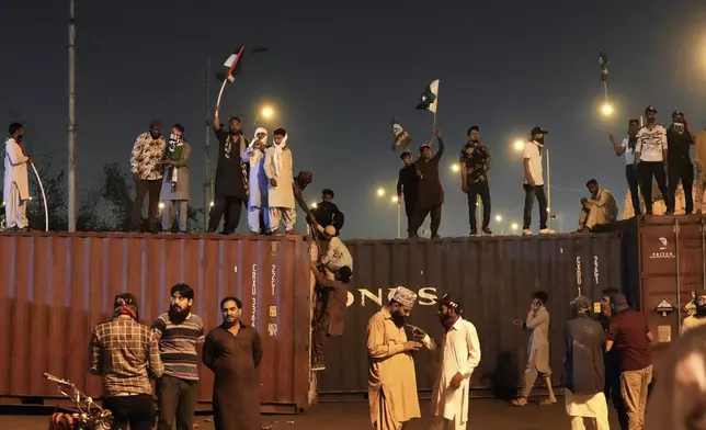 Supporters of the Pakistani religious group "Sunni Tehreek" chant slogans on the shipping containers placed by authorities to stop them for marching towards U.S. consulate during a rally against Israeli airstrikes and to show solidarity with Palestinian people living in Gaza, in Karachi, Pakistan Friday, April 11, 2025. (AP Photo/Fareed Khan)