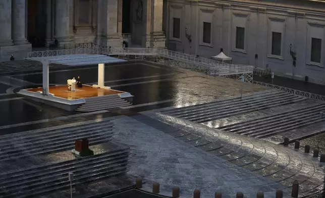 FILE - Pope Francis, white figure standing alone at center, delivers an Urbi et orbi prayer from the empty St. Peter's Square, at the Vatican, Friday, March 27, 2020. (Yara Nardi/Pool Photo via AP, File)