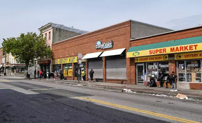 Litter lines the street as people walk and congregate on Pennsylvania Avenue near the Sandtown-Winchester neighborhood in Baltimore, Monday, April 14, 2025. (AP Photo/Stephanie Scarbrough)