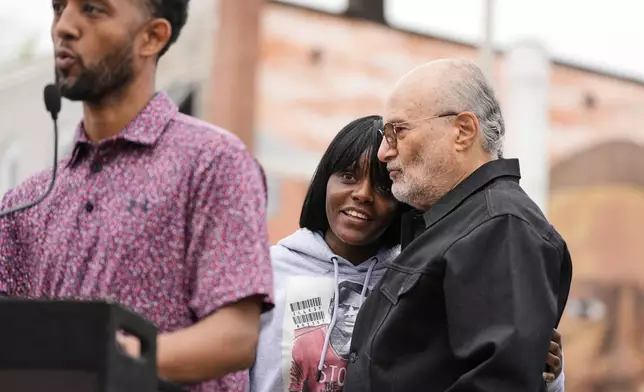 Fredricka Gray, twin sister of Freddie Gray, center, embraces William H. "Billy" Murphy, Jr. as Baltimore Mayor Brandon Scott, left, speaks at a memorial event commemorating the ten-year anniversary of the death of Freddie Gray, Saturday, April 19, 2025, in Baltimore. (AP Photo/Stephanie Scarbrough)