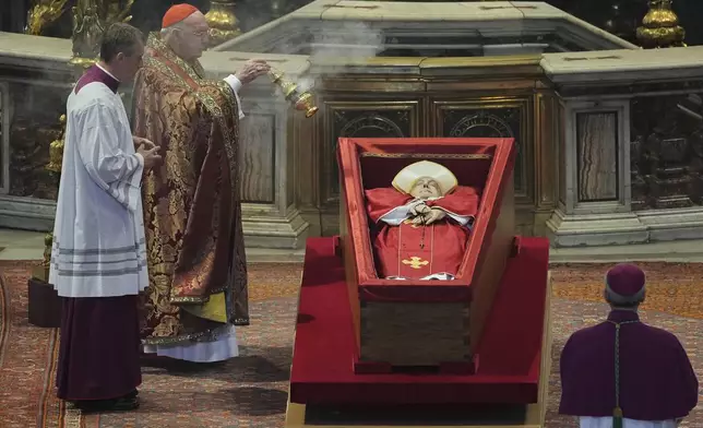Cardinal Camerlengo Kevin Joseph Farrell asperges incense around the body of Pope Francis inside St. Peter's Basilica at the Vatican, Wednesday, April 23, 2025, where he will lie in state for three days. (AP Photo/Andrew Medichini, Pool)