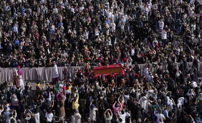 The ceremony with the Pope Francis' body, who will lie in state at St. Peter's Basilica for three days, pass through the crowd at the Vatican, Wednesday, April 23, 2025. (AP Photo/Gregorio Borgia)