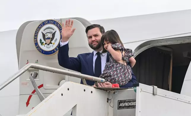 Vice President JD Vance disembarks Air Force Two while carrying his daughter Mirabel, upon arriving at G.B. Pastine–Rome Ciampino Airport, Friday April 18, 2025. (Kenny Holston/The New York Times via AP, Pool)