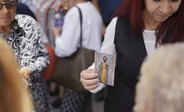 A parishioner holds a St. Mark religious card during St. Mark’s Fair, a month-long event honoring the saint, outside St. Mark's church in Aguascalientes, Mexico, Friday, April 25, 2025. (AP Photo/Eduardo Verdugo)