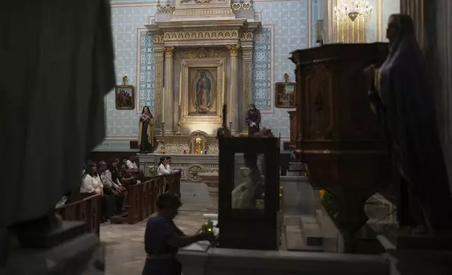 Devotees sit inside St. Mark's church, near an altar dedicated to the Virgin of Guadalupe, during St. Mark’s Fair, a month-long event honoring the saint, in Aguascalientes, Mexico, Friday, April 25, 2025. (AP Photo/Eduardo Verdugo)