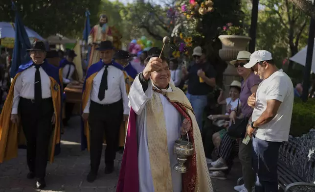 A priest sprinkles "holy water" on parishioners during St. Mark's Fair, a month-long event honoring the saint, outside St. Mark's Church in Aguascalientes, Mexico, Friday, April 25, 2025. (AP Photo/Eduardo Verdugo)