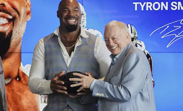Football player Tyron Smith, left, laughs as he and Dallas Cowboys team owner Jerry jones, right, hold a gift that was presented to Smith by the team after a news conference where Smith announced his retirement from the NFL at the Cowboys headquarters in Frisco, Texas, Wednesday, April 16, 2025. (AP Photo/Tony Gutierrez)