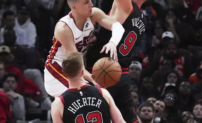 Miami Heat guard Tyler Herro, left top, drives to the basket against Chicago Bulls center Nikola Vucevic during the second half of an NBA play-in tournament basketball game in Chicago, Wednesday, April 16, 2025. (AP Photo/Nam Y. Huh)