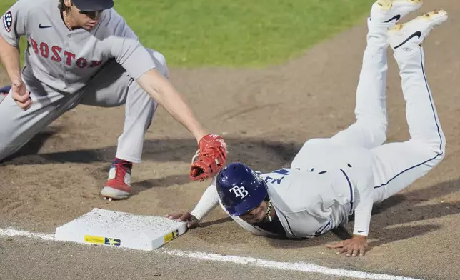 Tampa Bay Rays' Christopher Morel, right, dives back ahead of the tag by Boston Red Sox first base Triston Casas on a pickoff attempt during the fourth inning of a baseball game Wednesday, April 16, 2025, in Tampa, Fla. (AP Photo/Chris O'Meara)