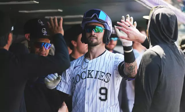 Colorado Rockies' Brenton Doyle is congratulated as he returns to the dugout after hitting a leadoff home run off Milwaukee Brewers starting pitcher Quinn Priester in the first inning of a baseball game Thursday, April 10, 2025, in Denver. (AP Photo/David Zalubowski)