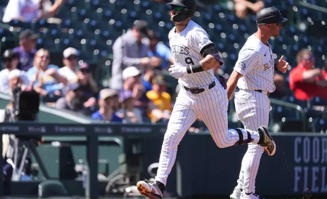 Colorado Rockies' Brenton Doyle, front, is congratulated after hitting a solo home run by third base coach Warren Schaeffer in the first inning of a baseball game against the Milwaukee Brewers, Thursday, April 10, 2025, in Denver. (AP Photo/David Zalubowski)