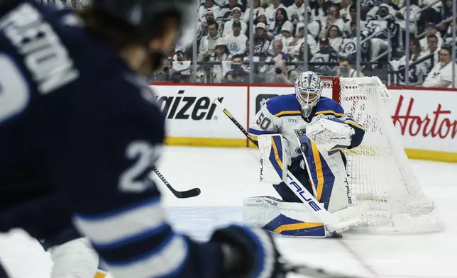 St. Louis Blues goaltender Jordan Binnington (50) saves a shot by Winnipeg Jets' Mason Appleton (22) during second-period NHL hockey playoff action in Winnipeg, Manitoba, Saturday, April 19, 2025. (John Woods/The Canadian Press via AP)
