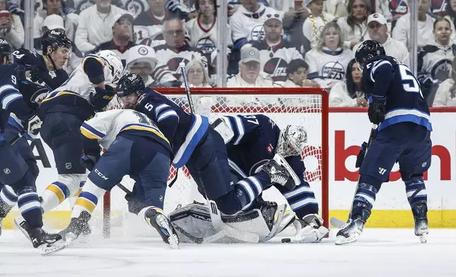 Winnipeg Jets' Luke Schenn (5) defends against St. Louis Blues' Robert Thomas (18) as Jets goaltender Connor Hellebuyck (37) saves the puck during second-period NHL hockey playoff action in Winnipeg, Manitoba, Saturday, April 19, 2025. (John Woods/The Canadian Press via AP)