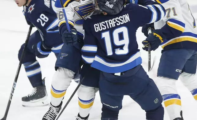 Winnipeg Jets' David Gustafsson (19) and St. Louis Blues' Zack Bolduc (76) collide during first period NHL playoff action in Winnipeg on Saturday, April 19, 2025. (John Woods/The Canadian Press via AP)