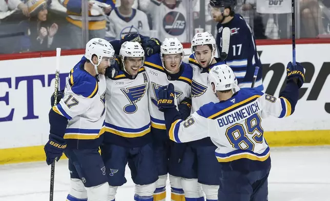 St. Louis Blues' Cam Fowler (17), Robert Thomas (18), Zack Bolduc (76), Jimmy Snuggerud (21) and Pavel Buchnevich (89) celebrate after Thomas' goal against the Winnipeg Jets during first-period NHL hockey playoff first-round action in Winnipeg, Manitoba, Saturday, April 19, 2025. (John Woods/The Canadian Press via AP)