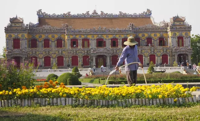 A gardener waters flowers outside the newly rebuilt Kien Trung Palace in the Imperial City within the Citadel of Hue, Vietnam, Feb. 21, 2024. (AP Photo/David Rising)