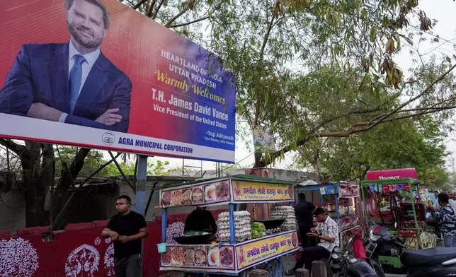 A vendor sells food on a road leading to the Taj Mahal under a banner welcoming U.S. Vice president JD Vance in Agra, India, Tuesday, April 22, 2025. (AP Photo/Rajesh Kumar Singh)