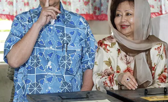 FILE - Malaysian Prime Minister Abdullah Ahmad Badawi, left, gestures as his wife Endon Mahmood looks on after casting their votes during the general election at a polling center in Kepala Batas, northern Malaysia, March 21, 2004. (AP Photo/Andy Wong, File)