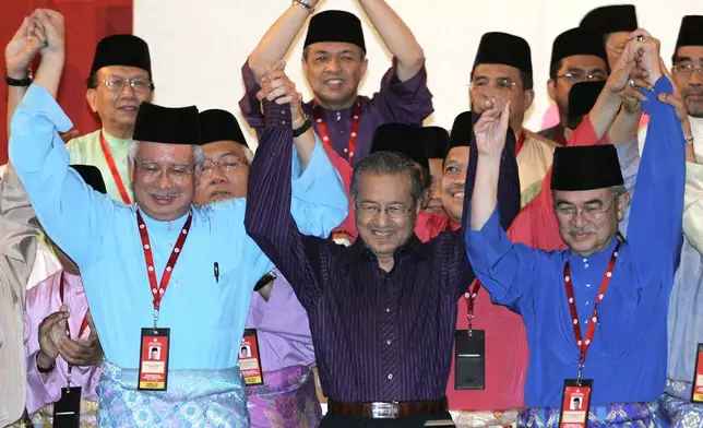 FILE - Malaysia's former Prime Minister Mahathir Mohamad, center, raises hands with then Prime Minister Abdullah Ahmad Badawi, right, and then Deputy Prime Minister Najib Razak at the United Malays National Organization (UMNO) general assembly in Kuala Lumpur, Malaysia, March 28, 2009. (AP Photo/Lai Seng Sin, File)