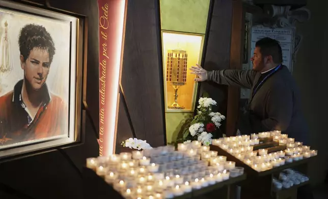 Rev. Cristopher Pujol prays at the heart relic of Carlo Acutis, the 15-year-old Italian boy who died in 2006 of leukemia and beatified in 2020, at the San Rufino Cathedral in Assisi, Italy, Wednesday, April 2, 2025. (AP Photo/Alessandra Tarantino)