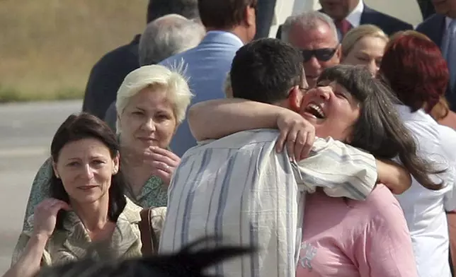 FILE - Bulgarian nurses Valentina Manolova Siropulo, left, Nasya Stoitcheva Nenova, second left, look on as Valia Georgieva Chervenisahka, right, hugs an unidentified man in front of the French presidential air plane after their arrival in the Bulgarian capital Sofia, July 24, 2007. (AP Photo, File)