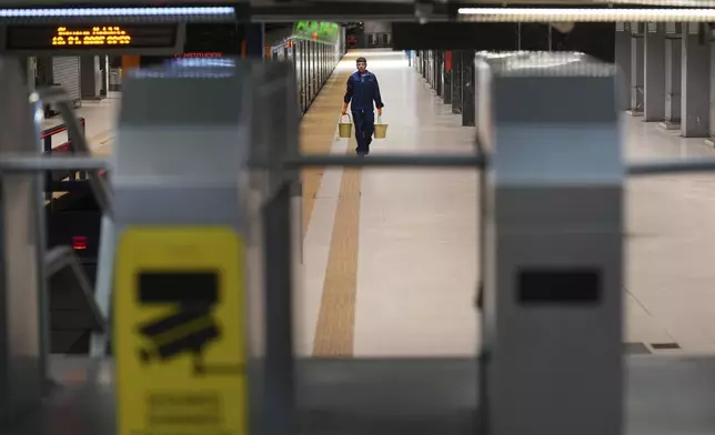 A lone worker walks at the Consititucion subway station during a general strike against the austerity measures of President Javier Milei in Buenos Aires, Argentina, Thursday, April 10, 2025. (AP Photo/Rodrigo Abd)