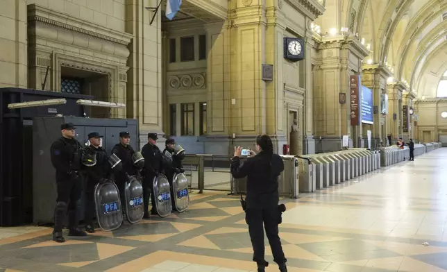 A policewomen takes a photo of her colleagues at Consititucion train station that is empty due to a general strike against the austerity measures of President Javier Milei in Buenos Aires, Argentina, Thursday, April 10, 2025. (AP Photo/Rodrigo Abd)