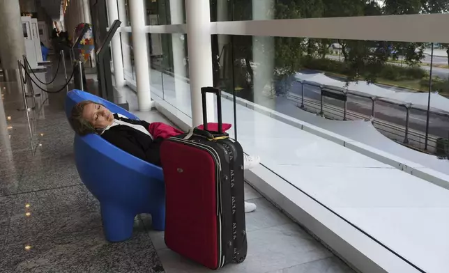 A stranded passenger sleeps at Jorge Newbery airport during a general strike against the austerity measures of President Javier Milei in Buenos Aires, Argentina, Thursday, April 10, 2025. (AP Photo/Rodrigo Abd)