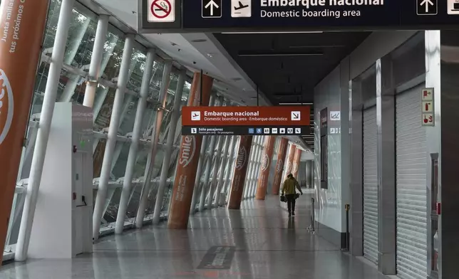 A lone worker walks inside the Jorge Newbery airport during a general strike against the austerity measures of President Javier Milei in Buenos Aires, Argentina, Thursday, April 10, 2025. (AP Photo/Rodrigo Abd)