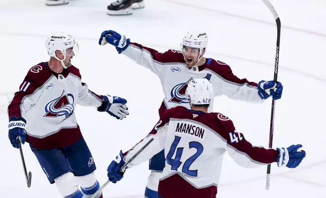 Colorado Avalanche players Brock Nelson (11), Devon Toews (7), and Josh Manson (42) celebrate after Toews' scored during a first-round NHL hockey playoff game against the Dallas Stars in Dallas, Saturday, April 19, 2025. (AP Photo/Gareth Patterson)