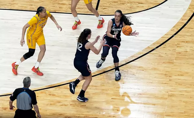 FILE - UConn guard Nika Muhl (10) passes the ball to teammate Ashlynn Shade (12) by the redrawn 3-point line during the first half of an Elite Eight college basketball game in the women's NCAA Tournament, Monday, April 1, 2024, in Portland, Ore. (AP Photo/Jenny Kane, File)