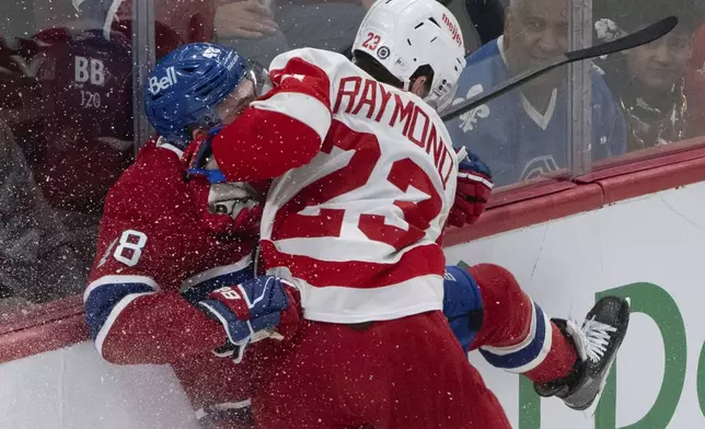 Montreal Canadiens' Lane Hutson (48) is checked into the boards by Detroit Red Wings' Lucas Raymond (23) during the second period of an NHL hockey game in Montreal on Tuesday, April 8, 2025. (Christinne Muschi/The Canadian Press via AP)