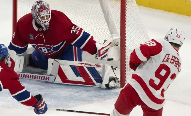 Montreal Canadiens goaltender Sam Montembeault (35) stops a shot by Detroit Red Wings' Alex DeBrincat (93) during the first period of an NHL hockey game in Montreal on Tuesday, April 8, 2025. (Christinne Muschi/The Canadian Press via AP)