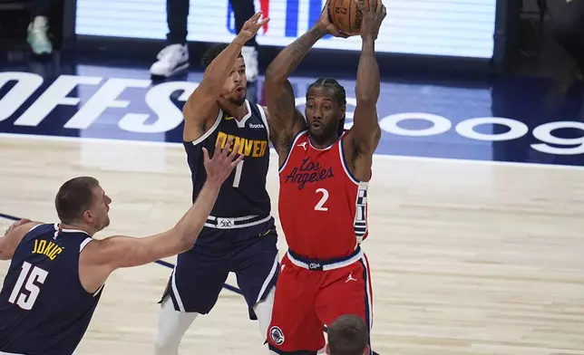 Los Angeles Clippers forward Kawhi Leonard, right, looks to pass the ball as Denver Nuggets center Nikola Jokic, left, and forward Michael Porter Jr., center, defend in the first half of Game 2 of a first-round NBA playoff series Monday, April 21, 2025, in Denver. (AP Photo/David Zalubowski)