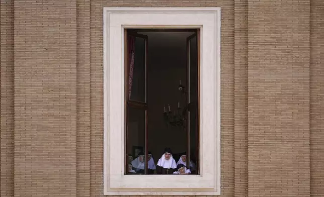 Nuns watch the funeral of Pope Francis from a window overlooking St. Peter's Square at the Vatican, Saturday, April 26, 2025. (AP Photo/Andreea Alexandru)
